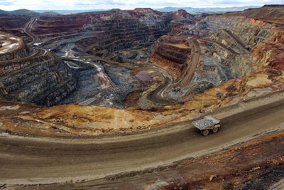 Open pit copper mine in Spain as seen from the viewpoint outside. One loaded dumptruck climbs the hauling road while the pit behind it shows all the red colours from different minerals